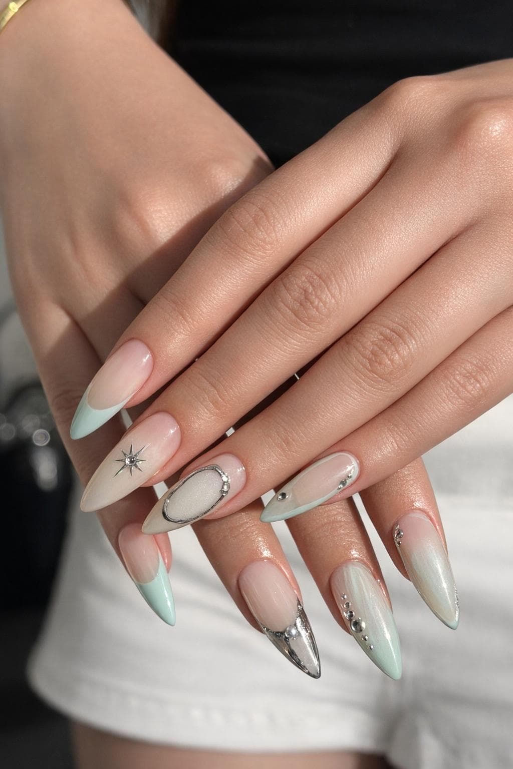 A set Nina created — soft mint and chrome almond-tip nails with a silver star and chrome accents